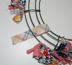 several pieces of fabric hanging from a metal rack on a white surface with scissors in it