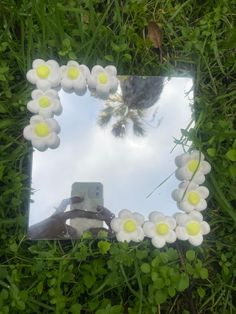 a mirror that is in the grass with flowers on it and a person taking a photo