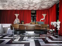 a room with black and white checkered flooring and red drapes on the ceiling