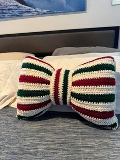 a crocheted bow tie sitting on top of a bed next to a pillow