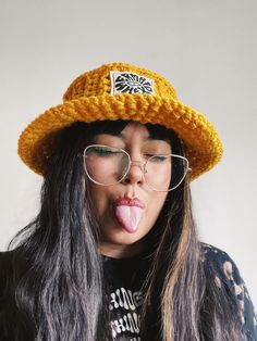 a woman sticking her tongue out wearing a yellow hat