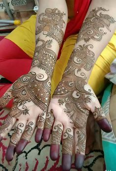 two hands with henna tattoos on them, one is showing off the intricate design