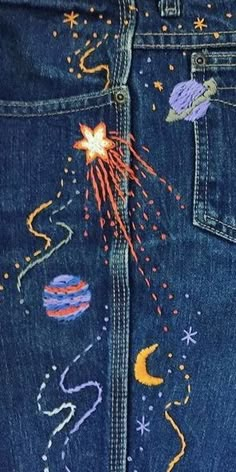 the back pocket of a pair of jeans with embroidered stars and planets on them,