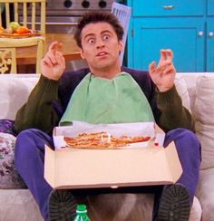 a man sitting on top of a couch holding a pizza in front of his face