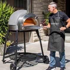 a man in an apron is cooking on a charcoal bbq grill with the door open