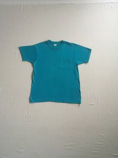 1980s blue t shirt label- Fruit Of The Loom pre-shrunk cotton right breast pocket made in USA single stitch good vintage condition, light wear- light collar stain, soft, faded label size M, see below measures, lying flat, shoulder- 18" chest- 19 1/2" sleeve- 6 3/4" length- 27" mannequin measures- bust-36", waist-27"     We do not offer returns or refunds unless something is grossly misrepresented. Please contact us within 2 business days of receiving to discuss any possible returns for this reas Blue Crew Neck T-shirt With Pockets, Vintage Solid Color Cotton T-shirt, Blue Vintage T-shirt With Relaxed Fit, Blue T-shirt With Pockets And Short Sleeves, Vintage Crew Neck Top With Pockets, Vintage Short Sleeve T-shirt, Vintage Blue Cotton T-shirt, Blue Vintage Style T-shirt With Relaxed Fit, Turquoise Cotton Short Sleeve T-shirt