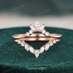 a rose gold wedding ring with pear shaped diamonds on the side and leaves in the middle