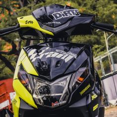 the front end of a yellow and black motorcycle with trees in the backgroud