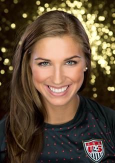 a woman with blue eyes and long brown hair smiling at the camera while wearing a black shirt