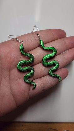 green snake earrings in the palm of someone's hand