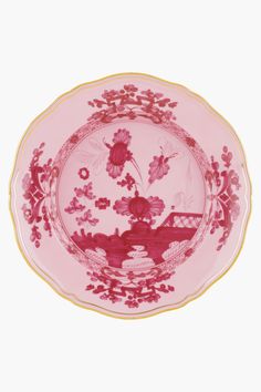 a pink and gold plate with flowers on the rim, in front of a white background