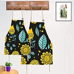 two aprons hanging from hooks in front of a wall with flowers and leaves on them