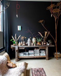 a living room filled with lots of furniture and plants on top of a wooden table