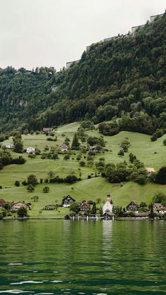 houses on the side of a hill overlooking a body of water with green hills in the background