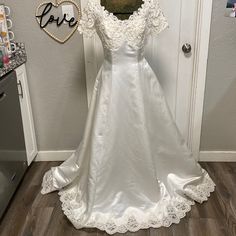 a white wedding dress is on display in front of a door with a love sign