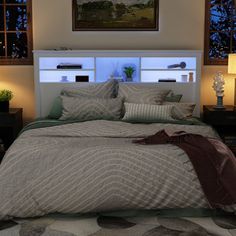 a large bed sitting under two windows in a bedroom next to a night stand and lamp