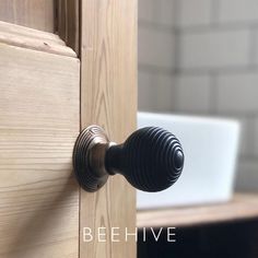 a close up of a door handle on a wooden cabinet with the words beehive above it