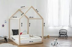 a white bed with a wooden house frame on top of it in front of a window