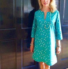 a woman standing in front of a door wearing a blue dress with white polka dots