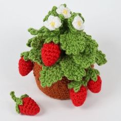 a crocheted potted plant with two strawberries