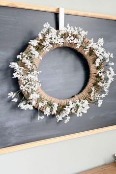 a wreath is hanging on the wall next to a chalkboard