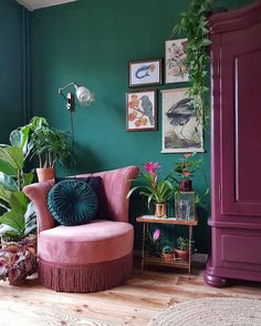 a living room with green walls and pink chair in front of a purple armoire