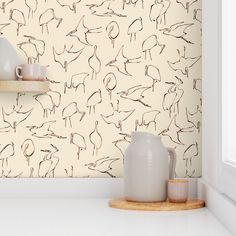 a kitchen counter with two white vases on it and a wallpapered background