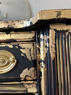 an old black and gold dresser with peeling paint