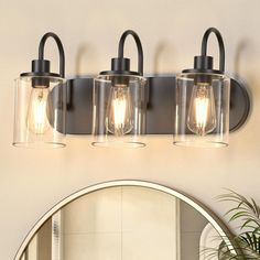 three light bathroom fixture with clear glass and black metal finish, on a white wall