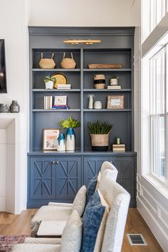 a living room with blue bookcases and white furniture in the corner, along with a large window