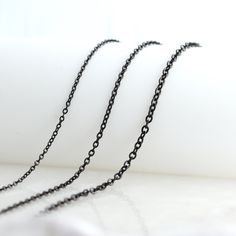 the black chain is hanging on the white surface