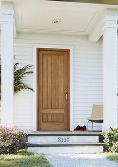 the front door of a white house with a chair and potted plant