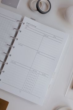 a binder, scissors, tape and other office supplies on a white table top