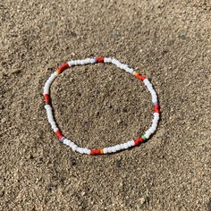 white seed beads with a pattern of shiny red, striped and solids strung on elastic please gently roll off and on to prolong its life handmade in venice, ca White Bohemian Stretch Bracelet For Festivals, Red Beaded Bracelets With Letter Beads For Beach, Casual White Beads For Beach, White Letter Beads Bracelets For Beach, White Bohemian Bracelets With Heart Beads, Casual White Beaded Bracelets For Festivals, Red Beaded Bracelets With Colorful Beads For Beach, Red Beaded Bracelets With Heart Beads For The Beach, Red Beaded Bracelet With Colorful Beads For Beach