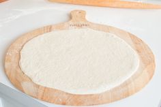 an uncooked pizza dough sitting on top of a cutting board