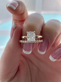 a woman's hand holding a ring with a diamond on it and two diamonds in the middle