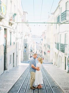 a man and woman are standing on the tracks in an alleyway between two buildings