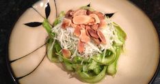 a white plate topped with green vegetables covered in nuts and shredded parmesan cheese