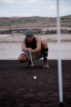 a man kneeling down to hit a golf ball