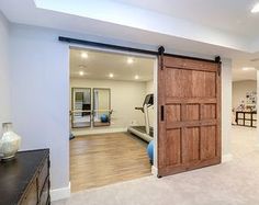 an exercise room with a treadmill and wooden door leading to the home gym area