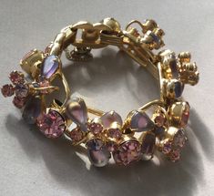 "Delizza and Elster, Juliana design with pink rhinestones and givre lavender satin glass teardrop accents. Beautiful, sparkling diamond like gems on this lovely link bracelet with a gold finish. A larger pink chaton is on a link that links two other ornate gem clusters. A total of five clusters and six large gem connectors. There is a chain guard as well as the very secure clasp. Wear this lovely bracelet on your fanciest outing. Quite a stunning and rare Juliana by Deliza and Elster from their Pink Crystal Bracelet With Sparkling Stones For Party, Pink Crystal-embellished Jewelry For Party, Pink Crystal Embellished Jewelry For Party, Elegant Pink Metal Crystal Bracelet, Pink Crystal Bracelet For Formal Occasions, Pink Crystal Bracelets For Formal Occasions, Formal Pink Crystal Bracelet, Pink Rhinestone Costume Jewelry, Pink Jeweled Metal Jewelry