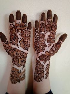 two hands with henna designs on them, one is brown and the other is white