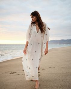 A natural white caftan made in handspun jamdani cotton fabric. It is accented with delicate handwoven motifs all over, V-shaped neckline, wide sleeves and side slits. This breathable caftan is mindfully crafted from sustainable materials and can be worn as a beach cover-up or worn out with slip. - Length: 51” - Fabric: Handwoven cotton - Color: Off-white White Chikankari Embroidery Kaftan For Vacation, Elegant Beach Kaftan With Chikankari Embroidery, Elegant White Kaftan For Festival, White Long Kurta For Beach, Long White Kurta For Vacation, White Chikankari Embroidery Kaftan For Beach, White Bohemian Kurta For Vacation, Bohemian Kaftan With Chikankari Embroidery For Beach, Bohemian Beach Kaftan With Chikankari Embroidery