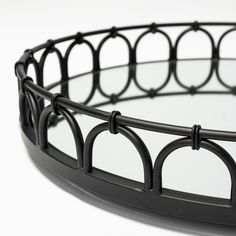 a round black metal tray with circles and bars on the rim, against a white background