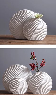 two white vases sitting on top of a wooden table next to each other with flowers in them