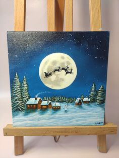 an easel with a painting on it and a santa sleigh in the sky