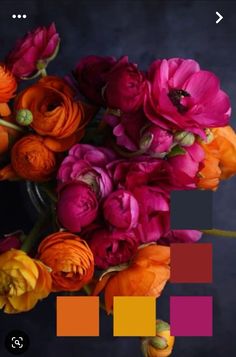 a vase filled with lots of colorful flowers on top of a wooden table in front of a dark background