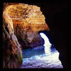 a cave with water coming out of it's entrance into the ocean and some rocks on either side