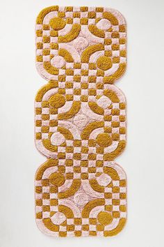 two yellow and pink rugs sitting on top of a white table next to each other