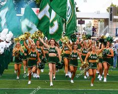 cheerleaders in green and gold outfits marching on the field at a football game